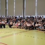 Pani dyrektor mówi do społeczności szkolnej zgromadzonej na sali gimnastycznej