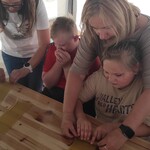 Nauczycielki pomagają uczniom zwijać świece