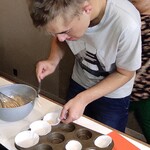 Uczestnik wkłada łyżką ciasto do papierowej foremki
