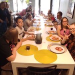 Uczestnicy warsztatów kulinarnych siedzą przy stole. przed nimi stoją talerze z pizzą