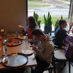 Uczestnicy półkolonii siedzą w pizzerni i jedzą pizzę