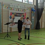 Pani dyrektor wręcza uczniowi zaproszenie po odbiór nagrody