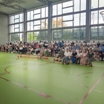 Społeczność szkolna zgromadzona na sali gimnastycznej słucha przemówienia pani dyrektor