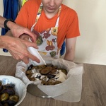 Nauczycielka pomaga uczniowi wsypać suche składniki na śliwki.