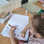 Uczennica koloruje kropki w zeszycie
