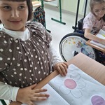 Uczennica siedzi przy stoliku. przed nią leży zeszyt z wklejonymi kropkami