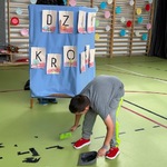 Uczeń zamiata śmieci, za uczniem parawan z papetem