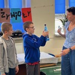 Uczeń próbuje zgnieść zakręconą butelkę.