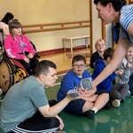 Uczeń wącha pojemnik z kawą podawany przez nauczyciela.