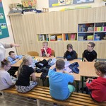 Uczniowie siedzą wokół stołu na którym leżą ubrania
