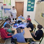 Uczniowie siedzą wokół stołu na którym leżą ubrania