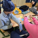 Uczeń siedzi przy stoliku w czapce zrobionej z niepotrzebnej odzieży