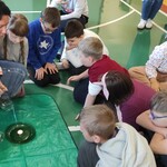 Nauczycielka i uczniowie obserwują palącą się świeczkę