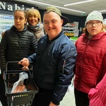 Grupa uczniów i nauczycielka stoją przed regałem z produktami spożywczymi  w  sklepie.