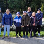 Grupa uczniów na tle kwiatów.