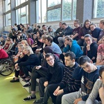 Uczniowie siedzą na trybunach w sali gimnastycznej