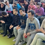 Uczniowie siedzą na trybunach w sali gimnastycznej