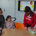 Lila rozpakowuje prezent. Obok stoją koleżanki z klasy