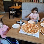 Uczennice siedzą przy stole na którym stoją pizze