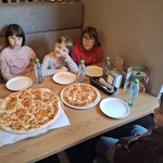 Uczennice siedzą przy stole na którym stoją pizze