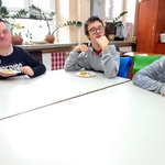 Uczniowie siedzą przy stole i jedzą frytki
