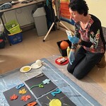 Nauczyciel pokazuje symbol, przed nim leżą cztery czarne kartki