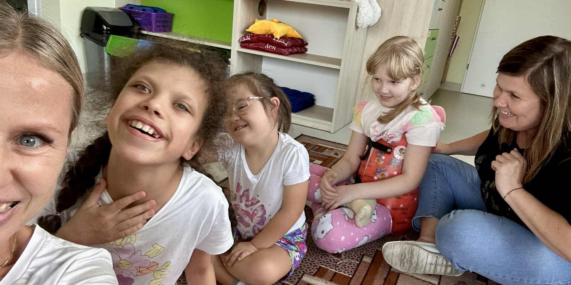Nauczycielki i uczennice siedzą po turecku na dywanie