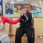 Uczeń siedzi pod parasolem, obok nauczyciel w stroju kucharza