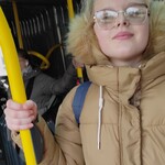 Uczennica stoi w autobusie i trzyma się poręczy