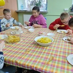Uczniowie siedzą przy stole i jedzą tort