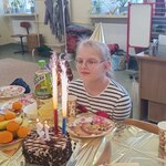 Jubilatka siedzi przy stole na którym stoi tort urodzinowy