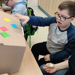 Uczeń dekoruje pudełko kolorowymi kwadratami