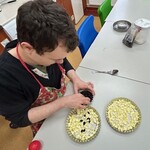 Uczeń wkłada żurawinę na pokrojone jabłka do małej tartaletki