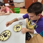 Uczeń wkłada żurawinę na pokrojone jabłka do małej tartaletki