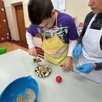 Uczeń posypuje kruszonką pokrojone jabłka