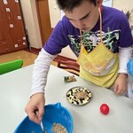 Uczeń posypuje kruszonką pokrojone jabłka