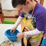 Uczeń posypuje kruszonką pokrojone jabłka