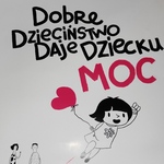 Fragment plakatu z napisem- Dobre Dzieciństwo Daje Dziecku MOC