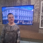 Uczeń stoi na tle zdjęć prezentowanych na ścianach muzeum