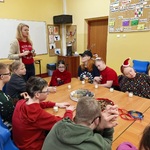 Pani prowadząca warsztaty stoi w szczycie stołu wokół którego siedzą uczniowie