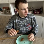 Uczeń zjada ciastko, przed nim talerz