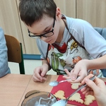 Uczeń siedzi przy stoliku i dekoruje pierniki