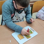 Uczeń siedzi przy stoliku i dekoruje pierniki