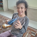 Uczennica siedzi na dywanie. Trzyma lusterko w ręku