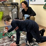 Uczeń ozdabia choinkę bombką układając ją na piance