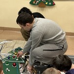 Uczeń ozdabia choinkę bombką układając ją na piance