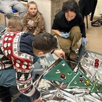 Uczeń ozdabia choinkę bombką układając ją na piance