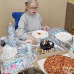 Uczniowie siedzą przy stole i jedzą pizzę