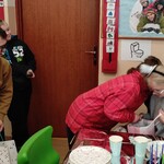 Koleżanka składa życzenia solenizantce. Obok stoją koledzy z prezentami