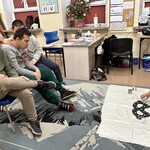 Nauczyciel ozdabia maskę, uczniowie przyglądają się
